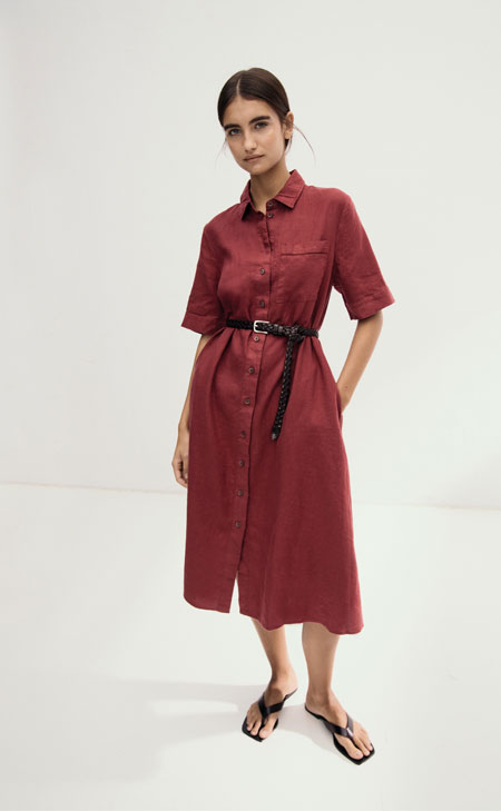 Frau in rotem Linen‑Kleid mit Taillengürtel, modern und clean im Studio inszeniert – hochwertiges Leinen für leichte Premium‑Sommerlooks.