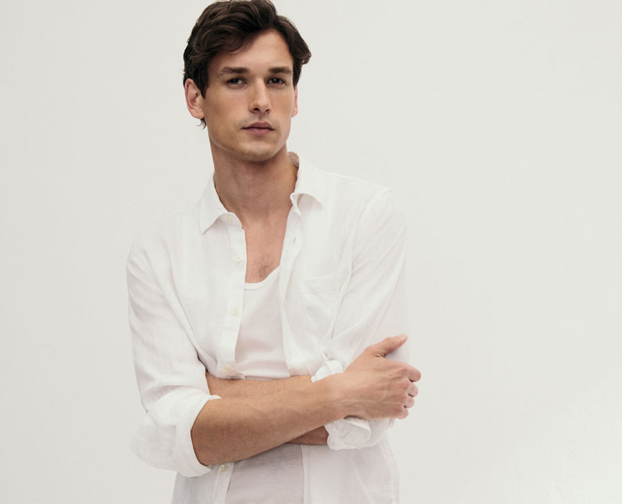 Mann in leichtem Linen‑Hemd und weißem Shirt, clean und modern im Studio inszeniert – natürliches Leinen für hochwertige Premium‑Sommerlooks.