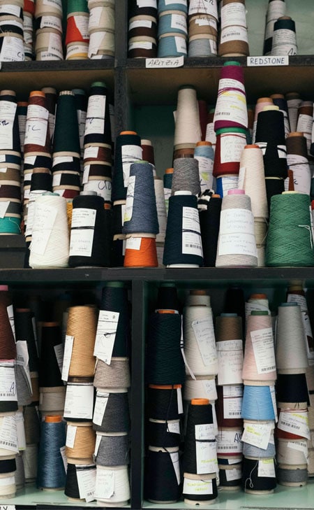 Regal mit Garnkonen in vielen Farben – hochwertige Knitwear‑Materialien für moderne Premium‑Strickmode.