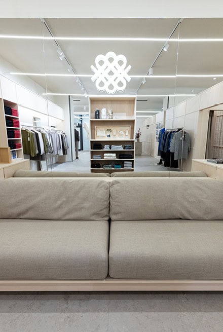 Sitzbereich im MAERZ Muenchen Store mit Sofa, Spiegelwand und Blick auf die präsentierte Strickkollektion.
